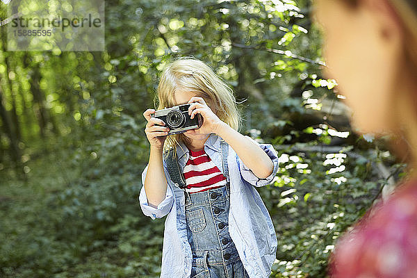 Mädchen fotografiert im Wald mit einer altmodischen Kamera