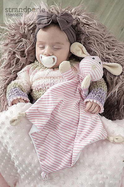 Porträt eines schlafenden Mädchens mit Haarband  Kuscheltier und Schnuller