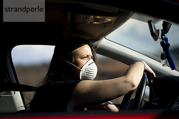 Frau im Auto mit Atemschutzmaske
