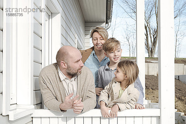 Glückliche Familie spricht auf der Veranda ihres Hauses