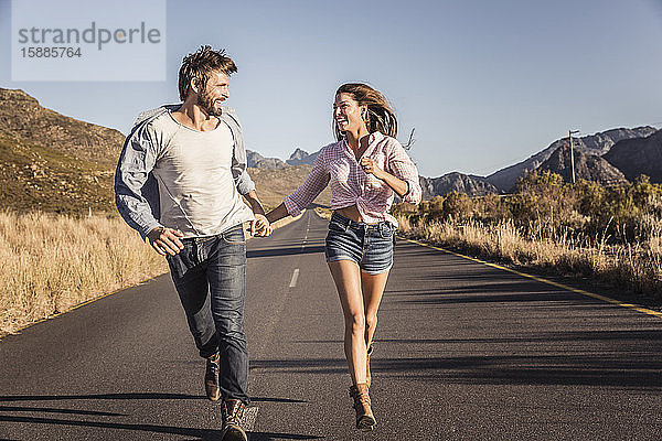 Glückliches Paar rennt auf einer Landstraße