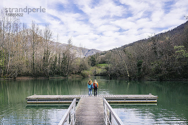 Rückenansicht von zwei Frauen mit Rucksäcken am Steg stehend  Valdemurio-Stausee  Asturien  Spanien