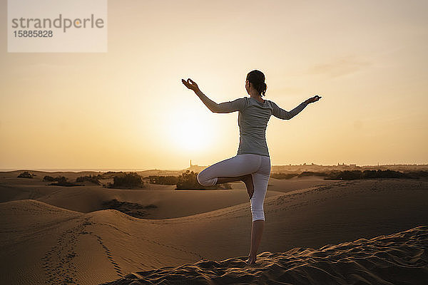 Frau praktiziert Yoga in Sanddünen bei Sonnenuntergang  Gran Canaria  Spanien
