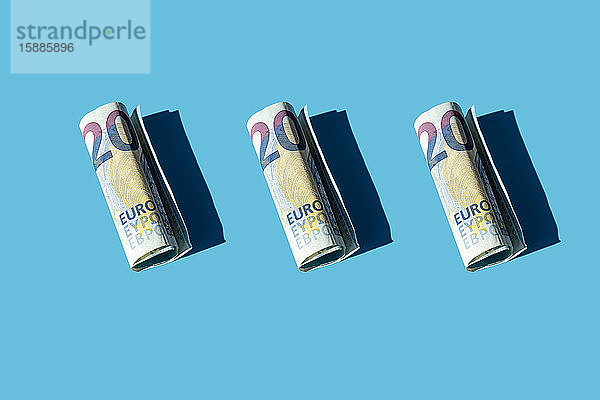 Zwanzig gerollte Euro-Banknoten auf blauem Hintergrund