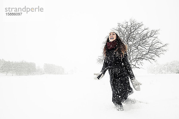 Glückliche junge Frau tanzt in Winterlandschaft