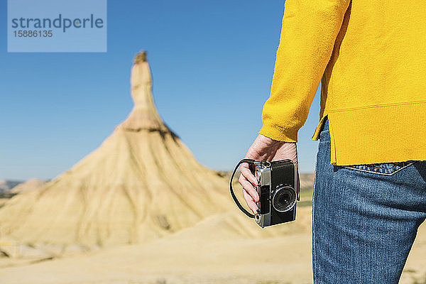 Frau hält eine Oldtimer-Kamera in der Wüstenlandschaft von Bardenas Reales  Arguedas  Navarra  Spanien