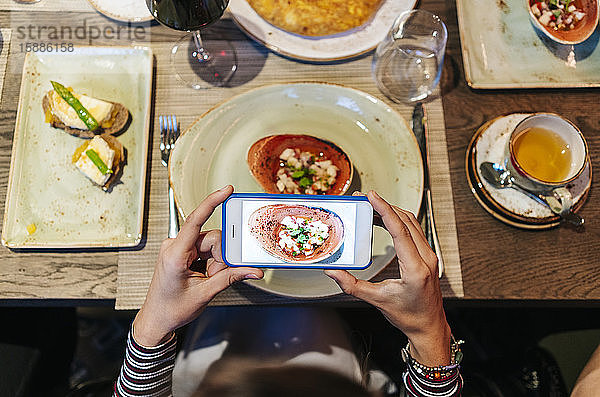 Frau im Restaurant  die mit einem Smartphone Essen fotografiert