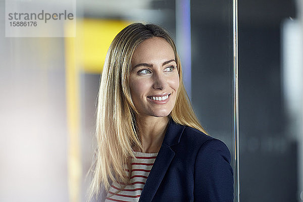 Porträt einer lächelnden Geschäftsfrau im Büro mit Blick zur Seite