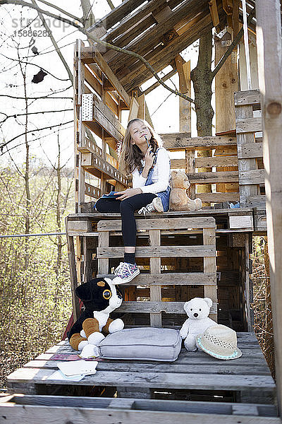 Nachdenkliches Mädchen spielt mit ihren Teddybären im Baumhaus