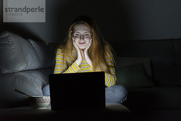 Junge Frau mit einer Laptop-Videokonferenz auf der Couch zu Hause