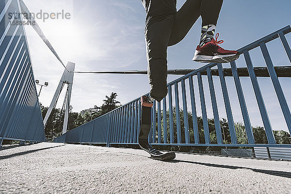 Niedriger Abschnitt eines behinderten Sportlers mit Beinprothese  der auf einer Brücke läuft