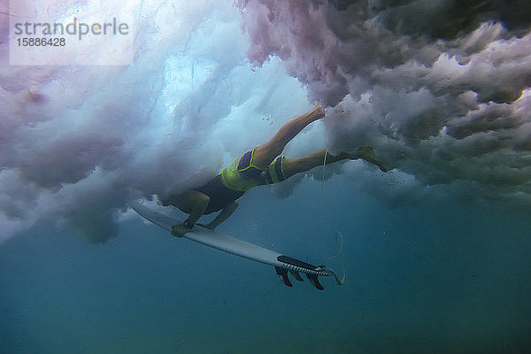 Indonesien  Unterwasseransicht eines erwachsenen Mannes  der mit einem Surfbrett in der Hand taucht