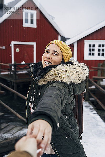 Porträt eines lächelnden Touristen  der die Hand eines Mannes an einer Hütte hält  Lofoten  Norwegen