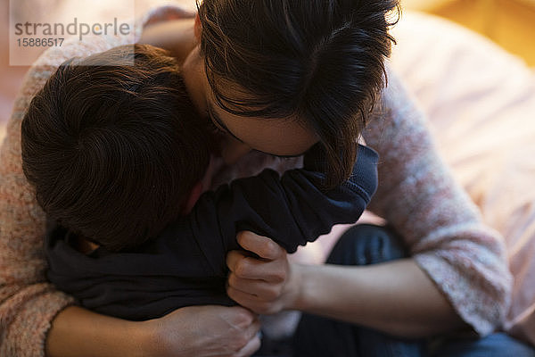 Mutter und kleiner Sohn umarmen sich zu Hause