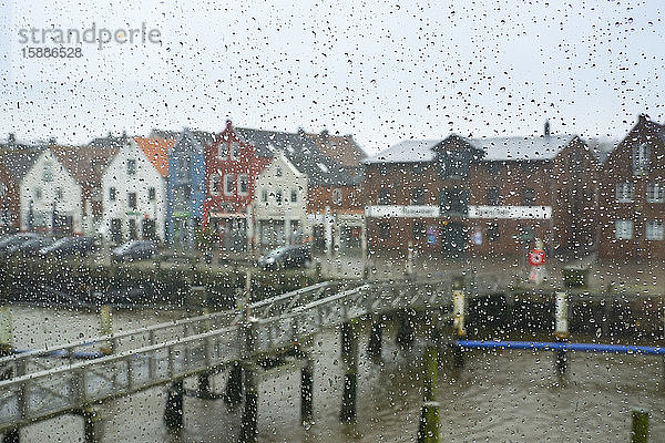 Deutschland  Schleswig-Holstein  Husum  Kanalbrücke und Häuser am Wasser  gesehen durch mit Regentropfen bedecktes Fensterglas