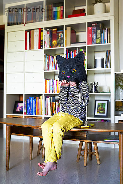 Kleines Mädchen sitzt zu Hause  imitiert Katze  trägt Maske