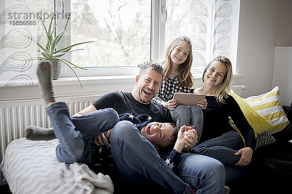 Porträt einer glücklichen Familie  die sich zu Hause auf der Couch vergnügt