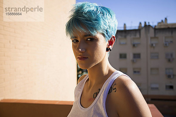 Androgyne junge Frau mit blauen Haaren auf dem Balkon