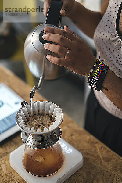 Frau  die in einer Kaffeerösterei arbeitet und frischen Filterkaffee zubereitet