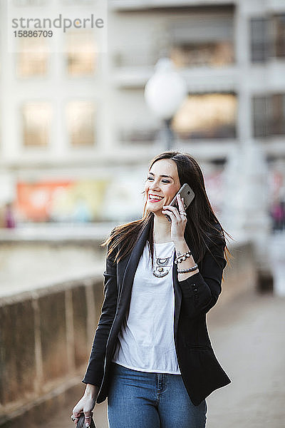 Porträt einer glücklichen Frau am Telefon beim Spaziergang in der Stadt
