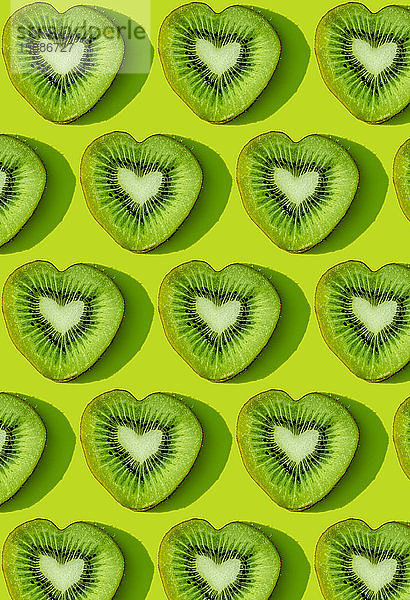 Herzförmige Kiwi-Fruchtscheiben Muster auf grünem Hintergrund