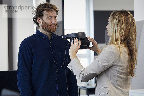 Geschäftsfrau und Geschäftsmann mit VR-Brille sprechen im Büro