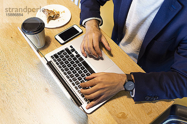 Schrägansicht eines Geschäftsmannes  der in einem Café am Laptop arbeitet