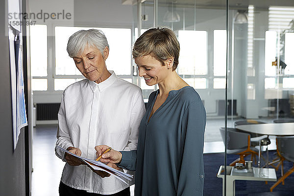 Zwei Geschäftsfrauen arbeiten zusammen auf Papier im Amt