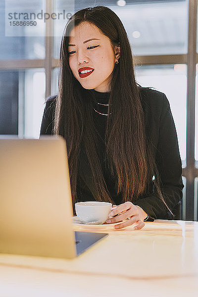 Lächelnde Geschäftsfrau mit Laptop in einem Cafe