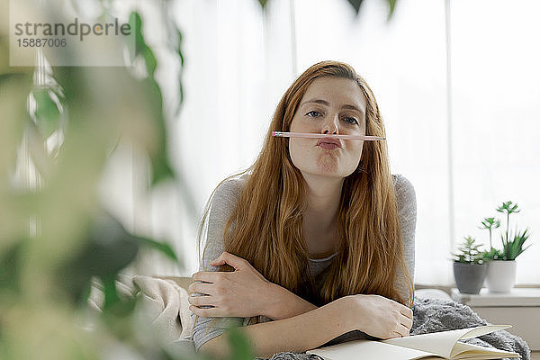 Porträt einer jungen Frau mit Bleistift und Notizbuch zu Hause