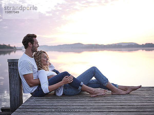 Romantisches Paar sitzt auf einem Steg am See