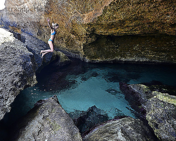 Frau springt in einer Grotte in klares Watr