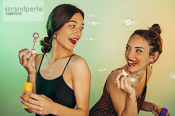 Porträt von zwei Freunden  die sich mit Seifenblasen vergnügen