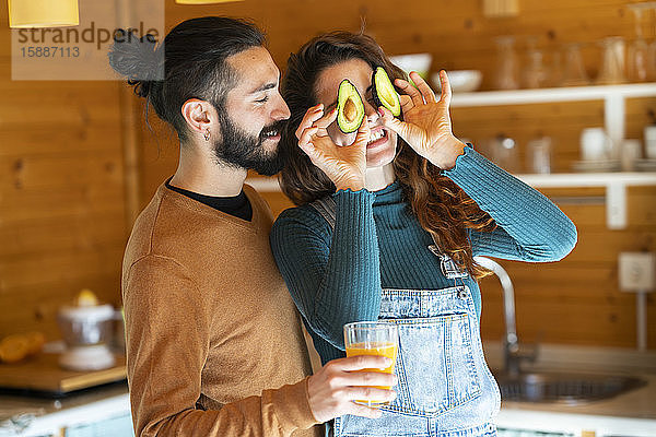 Verspieltes junges Paar vergnügt sich mit Avocados in einer Holzhütte