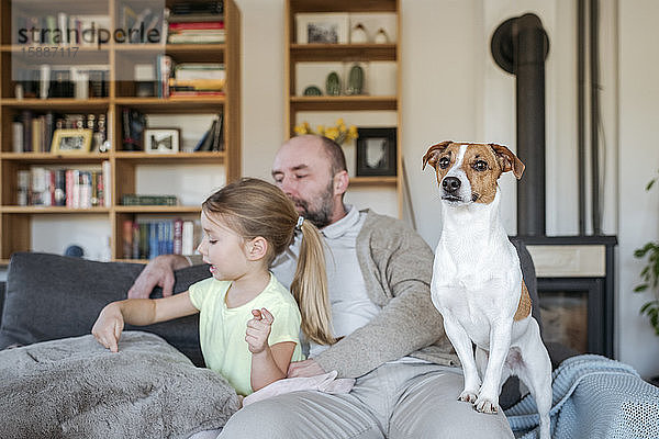 Vater  kleine Tochter und ihr Hund verbringen gemeinsam Zeit auf der Couch