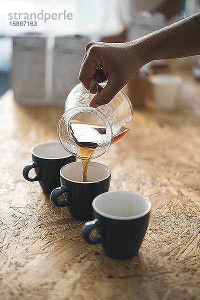 Frau gießt in einer Kaffeerösterei Kaffee in eine Tasse
