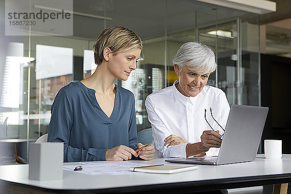 Zwei Geschäftsfrauen arbeiten zusammen mit Laptop im Büro