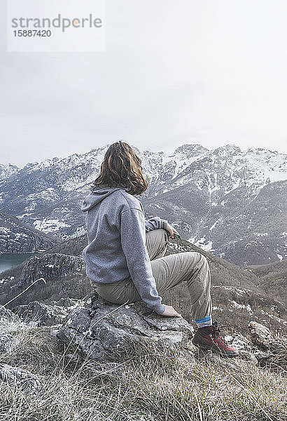 Rückenansicht einer jungen Frau  die auf einem Felsen sitzt und auf die Aussicht schaut  Provinz León  Spanien