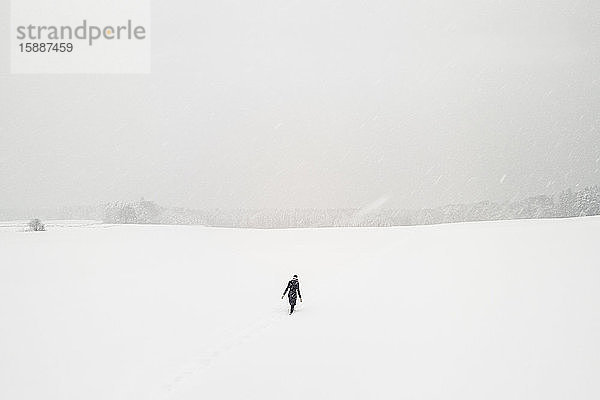 Frau geht allein in schneebedeckter Landschaft