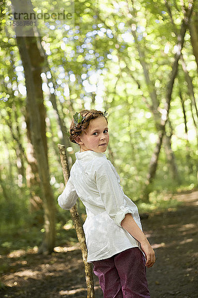 Bildnis eines Mädchens mit Holzstock beim Waldspaziergang