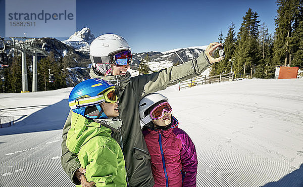 Mutter mit ihren Kindern  die einen Selfie auf der Skipiste machen