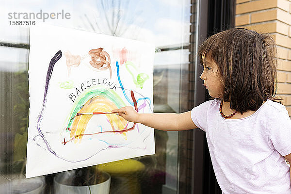 kleines Mädchen  das ein Bild auf das Fenster malt