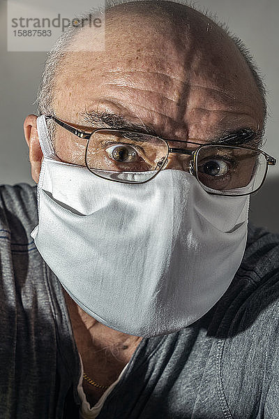 Porträt eines älteren Mannes mit chirurgischer Maske in Panik