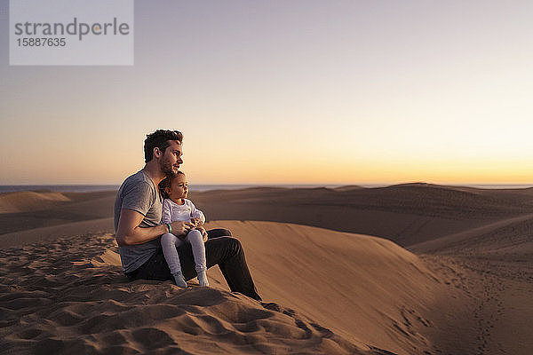 Vater sitzt mit seiner Tochter bei Sonnenuntergang in den Sanddünen  Gran Canaria  Spanien