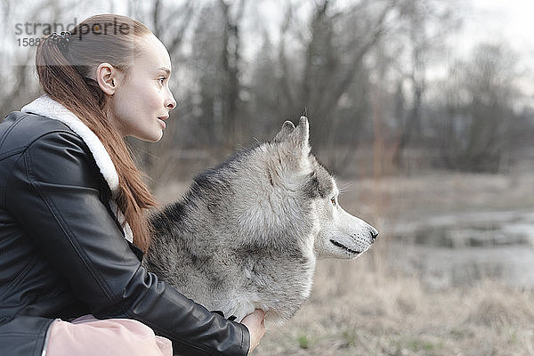 Frau und ihr Husky schauen auf Distanz