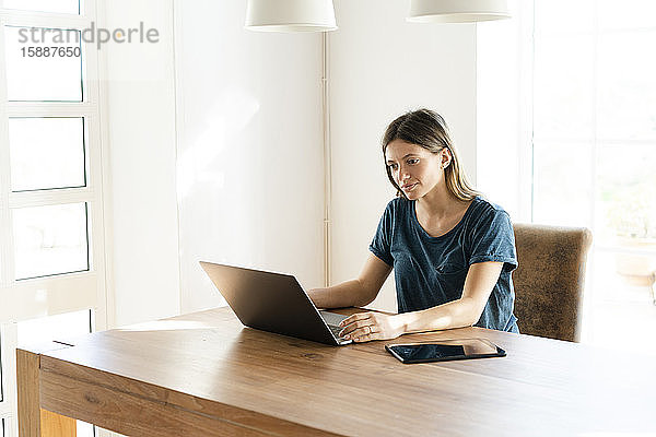 Junge Frau arbeitet zu Hause an ihrem Laptop im Home-Office