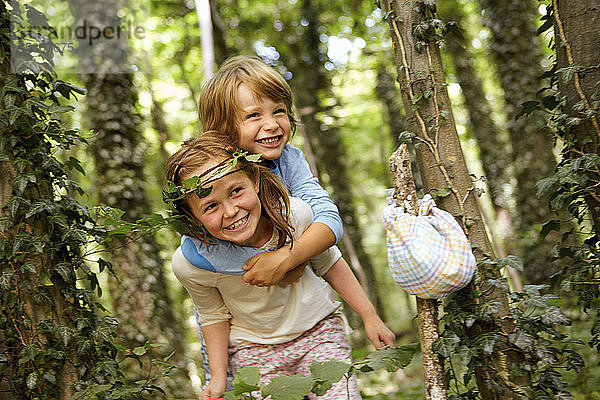 Mädchen trägt Jungen huckepack im Wald