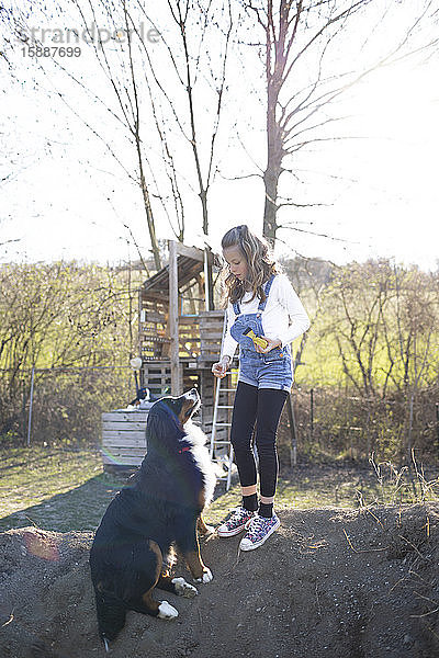 Mädchen spielt mit ihrem Hund im Garten