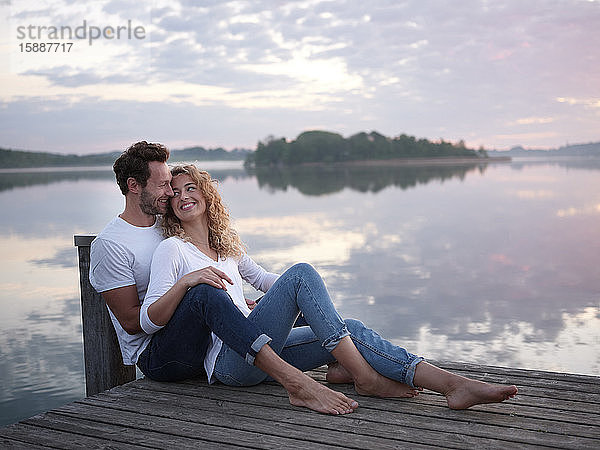 Romantisches Paar sitzt auf einem Steg am See