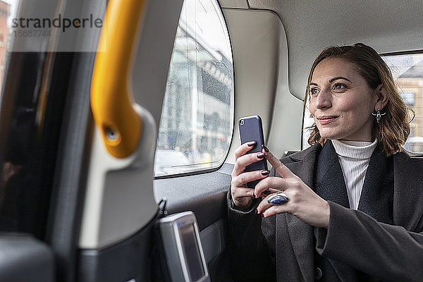 Geschäftsfrau auf dem Rücksitz eines Taxis  die aus dem Fenster schaut  London  UK